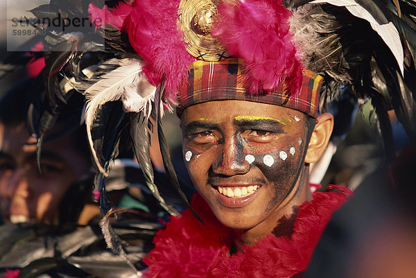 Porträt eines Mannes mit Gesichts Dekoration und Kopf-Kleid mit Federn am Mardi Gras Karneval  Dinagyang in Iloilo City  Insel Panay  Philippinen  Südostasien  Asien