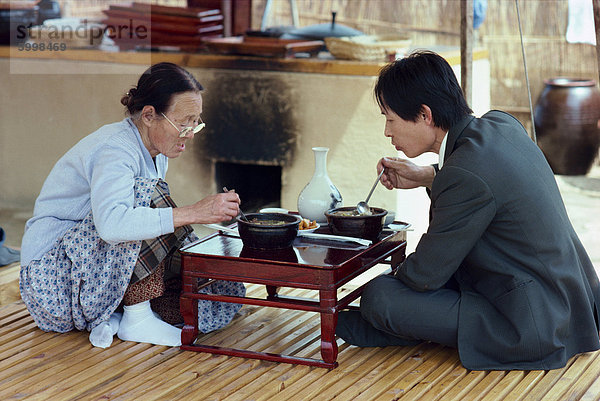 Zwei Personen Essen aus einem niedrigen Tisch im Restaurantbereich des Folk Village in Südkorea  Asien