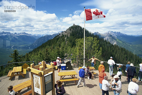 Touristen unterhalb der kanadischen Flagge auf Sulphur Mountain im Banff-Nationalpark in Alberta  UNESCO Weltkulturerbe  Kanada  Nordamerika