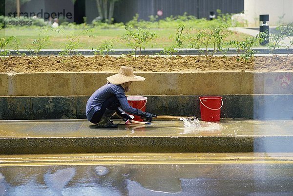 Eine ältere Frau in einem Strohhut wäscht das Pflaster des Raffles Place in der finanziellen Bezirk von Singapur  Südostasien  Asien