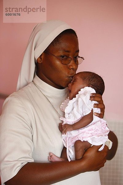 Franziskaner Schwester hält ein Waisenkind in Kinderkrippe und Kindergarten Ausführen von katholischen Nonnen  Lome  Togo  Westafrika  Afrika