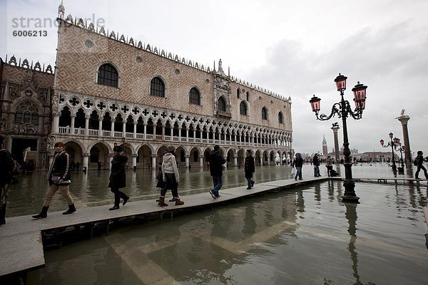 Touristen zu Fuß auf Stege während der Flut in den Markusplatz  Dogenpalast im Hintergrund  Venedig  UNESCO World Heritage Site  Veneto  Italien  Europa
