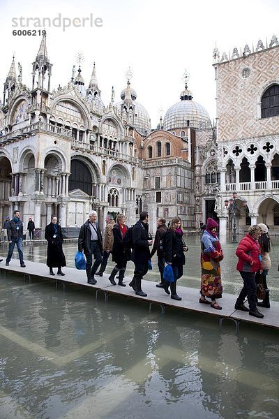 Touristen zu Fuß auf Stege bei Flut in Saint Mark's Square  Venedig  UNESCO World Heritage Site  Veneto  Italien  Europa