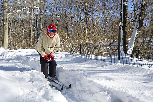 Eine Frau auf Langlauf-Ski im Central Park nach einem Schneesturm  New York City  New York State  Vereinigten Staaten von Amerika  Nordamerika
