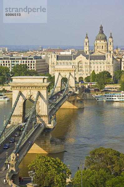 Verkehr fahren über die Donau  auf der Kettenbrücke (Szechenyi Lanchid)  mit dem Gresham Hotel und St. Stephans Basilika Kuppel hinter  Budapest  Ungarn  Europa