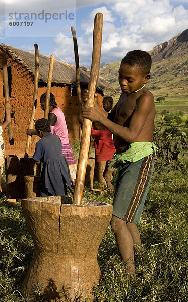 Ein lokaler Junge schleift Hirse per Hand mit einem riesigen Mörser und Pistill  Tsaranoro Velley  Andringitra Nationalpark  in der Nähe von der provinziellen Stadt von Fianarantsoa  südlichen Madagsacar  Afrika