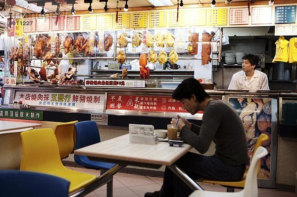 Mann im Café mit hängenden gebratene Ente und Schweinefleisch und chinesische Menüs  Hong Kong  China  Asien