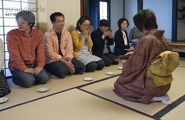 Menschen empfangen Schalen Tee aus der Hostess an einer japanischen Teezeremonie  Japan  Asien