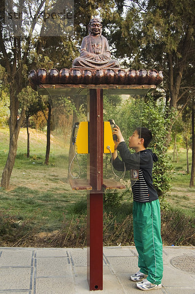 Ein Junge mit eine Mönch verziert-Telefonzelle im Shaolin Tempel  Geburtsort von Kung Fu Kampfkunst  Shaolin  Provinz Henan  China  Asien