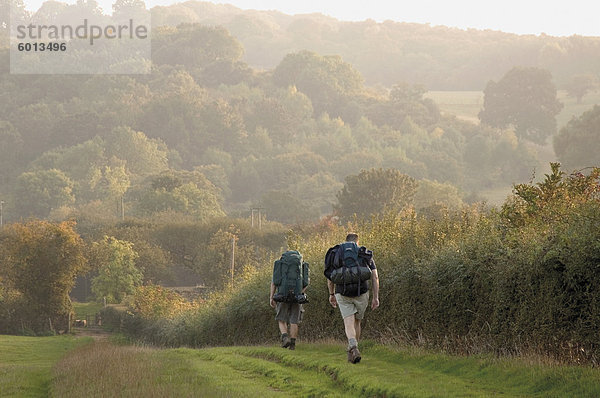 Zwei Wanderer mit Rucksäcken auf dem Fußweg Cotswold Weise Alicante Dorf  The Cotswolds  Gloucestershire  England  Vereinigtes Königreich  Europa