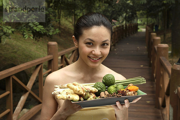 Mädchen mit einem Tablett voller Zutaten für Jamu  das indonesische Kräuter-Elixier  Indonesien  Südostasien  Asien