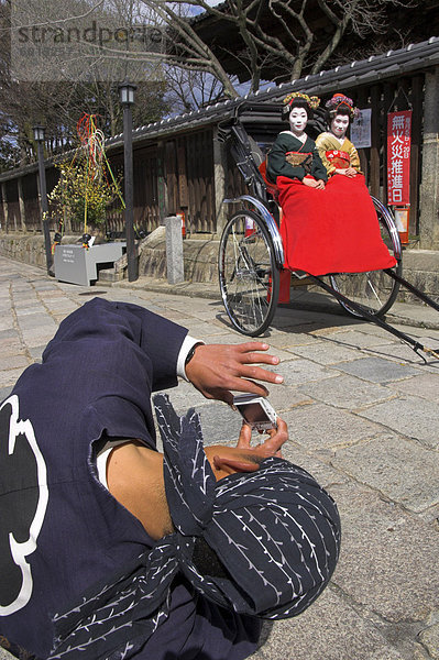 Treiber  die Aufnahme von zwei Geishas in traditionellen Kleidern posieren auf eine Rikscha  Higashiyama-Viertel  Kyoto  Kansai  Honshu  Japan  Asien