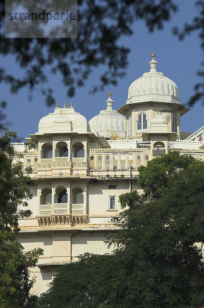 Weisse südliche Fassade des Stadtschlosses durch Bäume betrachtet  Altstadt  Udaipur  Rajasthan Zustand  Indien  Asien