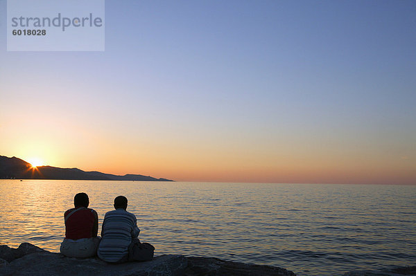 Paar  sitzen am Deich beobachten Sonnenuntergang