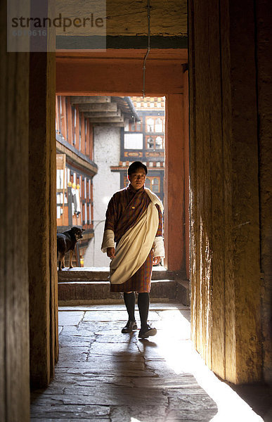 Lokale Mann in Nationaltracht Hintergrundbeleuchtung durch Abend Sonnenlicht auf der Jakar Dzong  Jakar  Bumthang  Bhutan  Asia