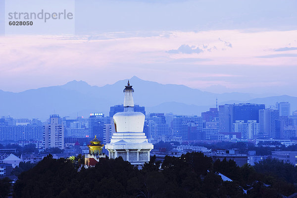 Eine beleuchtete Weiße Pagode und Gebäude der Stadt bei Sonnenuntergang  Beihai-Park  Peking  China  Asien