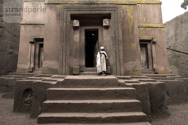 Ein Priester steht am Eingang zu den Felskirchen Kirche von Bet Giyorgis (St. Georg)  in Lalibela  UNESCO Weltkulturerbe  Äthiopien  Afrika