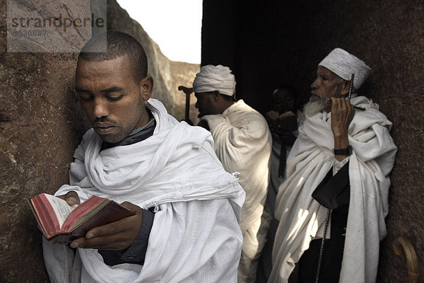 Ein Mann liest aus der Bibel auf die Felskirchen Kirche von Bet Maryam  in Lalibela  UNESCO-Weltkulturerbe  Äthiopien  Afrika