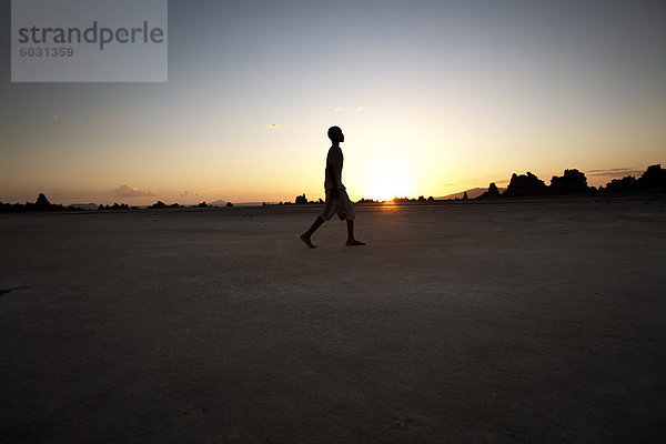 Ein Junge führt durch die öde Landschaft des Lac Abbe  Dschibuti  Afrika