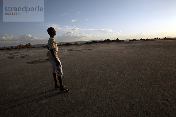Ein Junge steht in der öden Landschaft des Lac Abbe  Dschibuti  Afrika