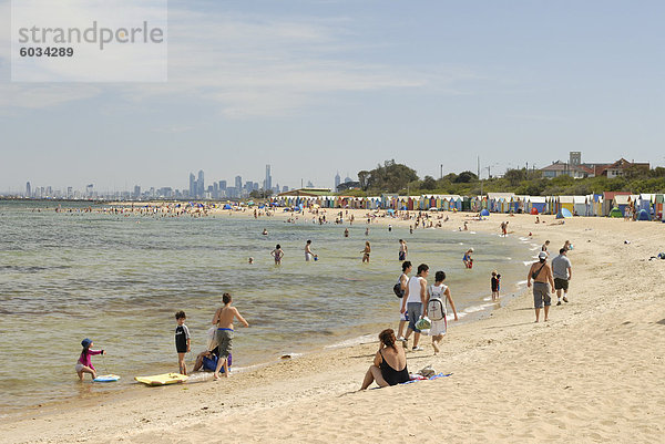 Strand-Szene mit Strandhütten auf Brighton Beach  Brighton  und im Hintergrund Wolkenkratzern der Stadt Melbourne  Victoria  Australien  Pazifik