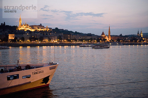 Schifffahrt auf der Donau mit Matyas Kirche und Burgviertel beleuchtet in Ferne  Budapest  Ungarn  Europa