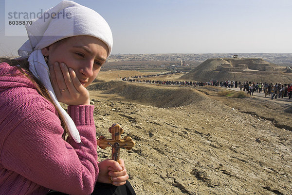 Weibliche Pilger halten eines Kreuzes mit Prozession zum Jordan im Hintergrund  während Christian orthodoxe Zeremonie am Dreikönigstag  Qasr el Yahud  Israel  Naher Osten