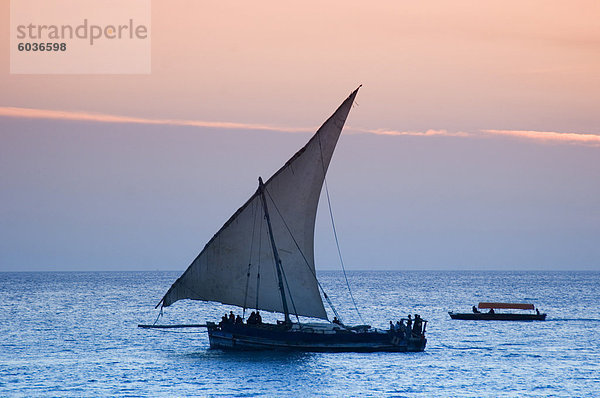 Einem traditionellen hölzernen Dhow Segeln in der Nähe von Stone Town bei Sonnenuntergang  Sansibar  Tansania  Ostafrika  Afrika