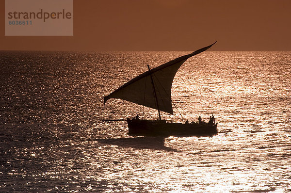 Eine Dhow Segeln bei Sonnenuntergang in der Nähe von Stone Town  Sansibar  Tansania  Ostafrika  Afrika