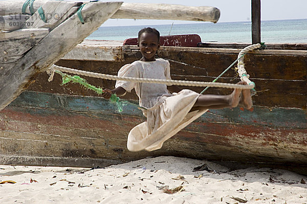 Ein Mädchen auf einer behelfsmäßigen Schaukel am Strand von Nungwi  Sansibar  Tansania  Ostafrika  Afrika