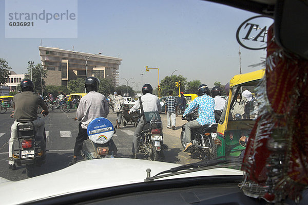 Menschen auf Motorrädern warten an der Ampel mit modernen Gebäude im Hintergrund  gesehen von innen ein Taxi  in der Nähe von Connaught Place  Neu Delhi  Delhi  Indien  Asien