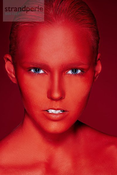 Porträt der jungen Frau mit Gesicht in roten gemalt  Studioaufnahme
