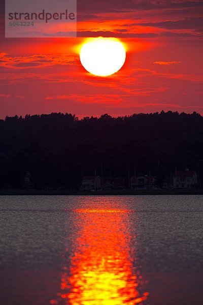 Rote Sonne reflektiert in Wasser bei Sonnenuntergang
