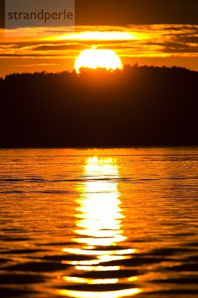 Orange Sonne reflektiert in Wasser bei Sonnenuntergang