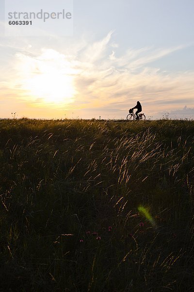 Ein Mann  mit dem Fahrrad bei Sonnenuntergang