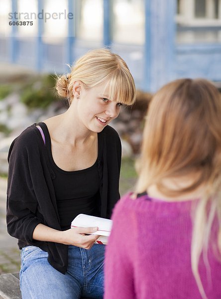 Zwei Teenager auf Bank sitzen