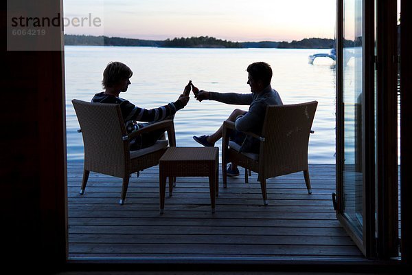 Zwei junge Männer Toasten Getränke auf der Terrasse am Meer