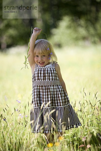 Glückliches junges Mädchen spielen im Weizenfeld