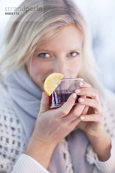 Frau trinkt Tee mit Zitrone Keil drinnen