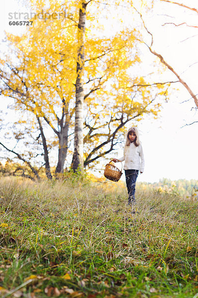 Mädchen gehen durch Herbstliche Landschaft mit Korb