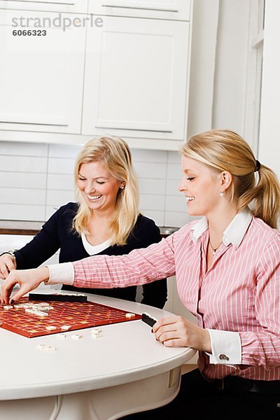 Zwei junge Frauen spielen Brettspiel in Küche