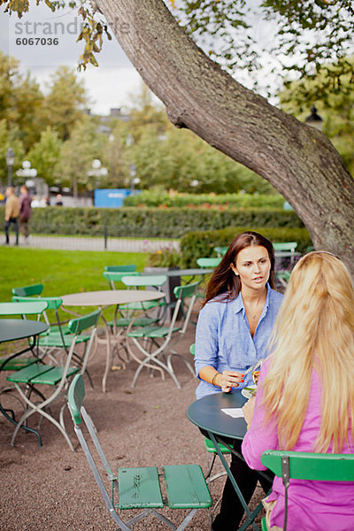 Zwei Frauen sitzen im Café im freien