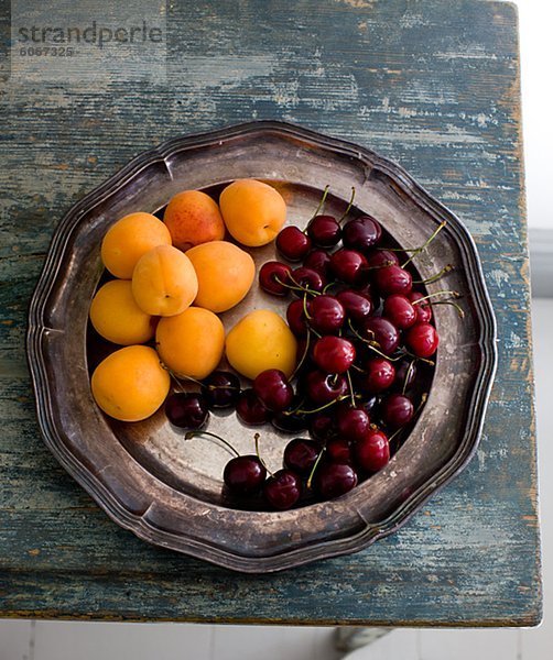 Aprikosen und Kirschen auf silbernen Tablett