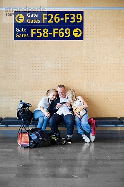 Vater mit zwei Töchtern sitzen am Flughafen
