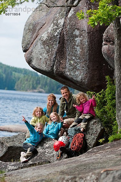 Familie mit vier Kinder sitzen in der Nähe von Felsen mit ihren Kletterausrüstung