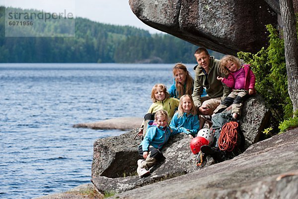 Familie mit vier Kinder sitzen in der Nähe des Felsens mit ihren Kletterausrüstung