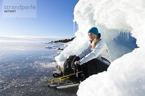 Frau sitzt auf dem Eis  Lächeln