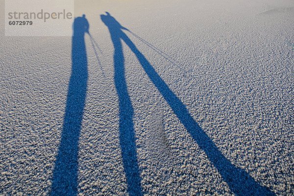 Schatten zweier Menschen auf dem Eis