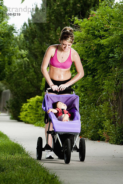 Frau  lächeln  Weg  rennen  Athlet  Kinderwagen  joggen  jung  Vorort  Baby