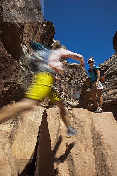 zwischen  inmitten  mitten  Felsbrocken  Frau  springen  Schlucht  Freund  Utah